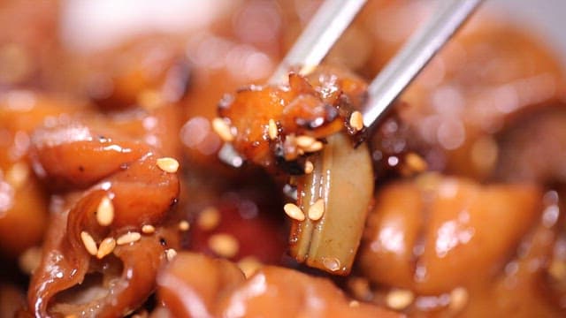 Chopsticks holding glazed seasoned pork intestines