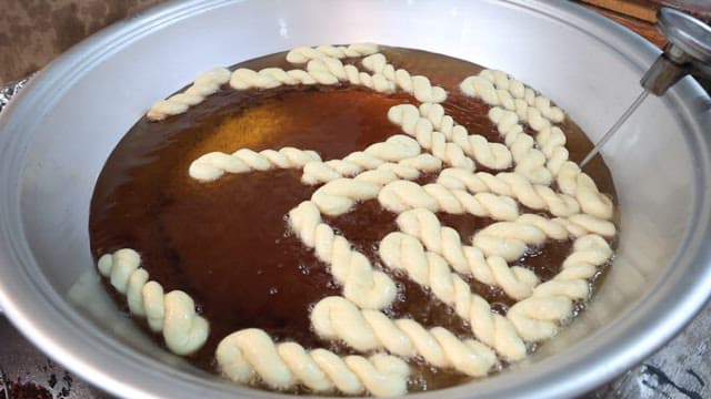 Frying traditional twisted donut dough in oil