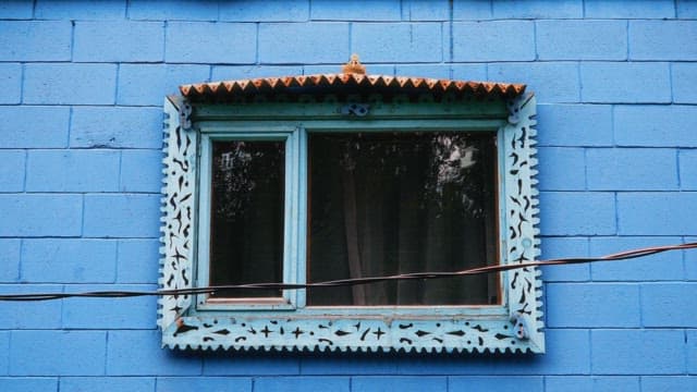Vibrant blue wall of the building with a decorated window frame