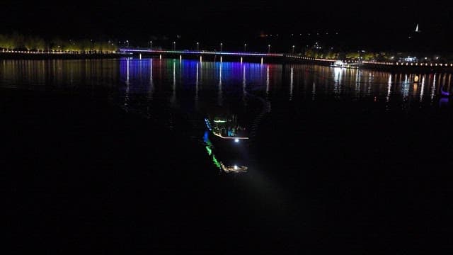 Boat Cruising at Night with Colorful Lights of Bridge