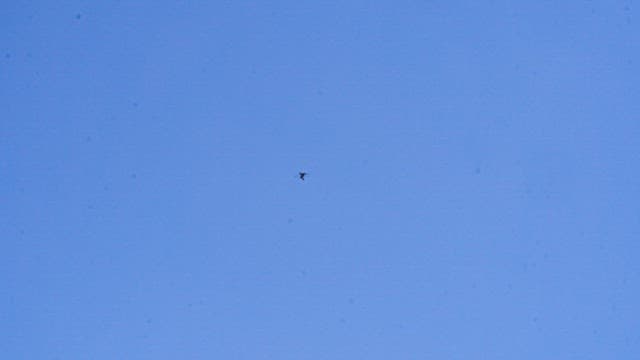 Hang-glider soaring high in the clear blue sky