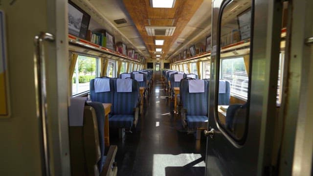 Inside a bright and empty railway carriage with large windows on a sunny day