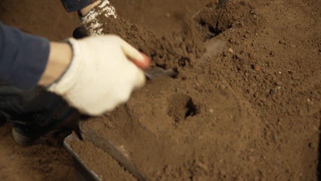 Hands shaping soil with a tool
