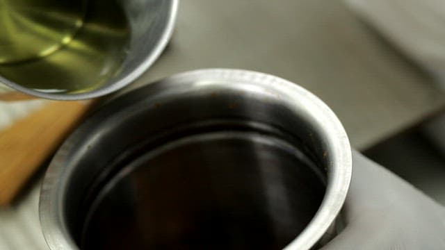 Pouring oil into a metal container