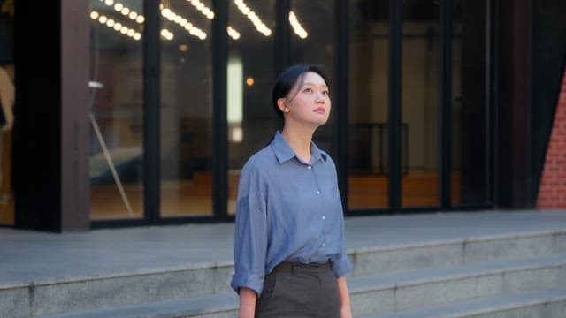 Woman looking up outside a building