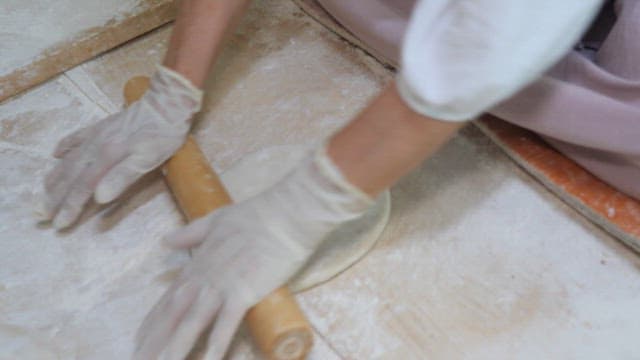 Kneading dough on a floured surface using a rolling pin