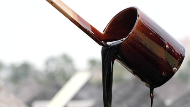 Pouring thick black soy sauce from a wooden ladle outdoors