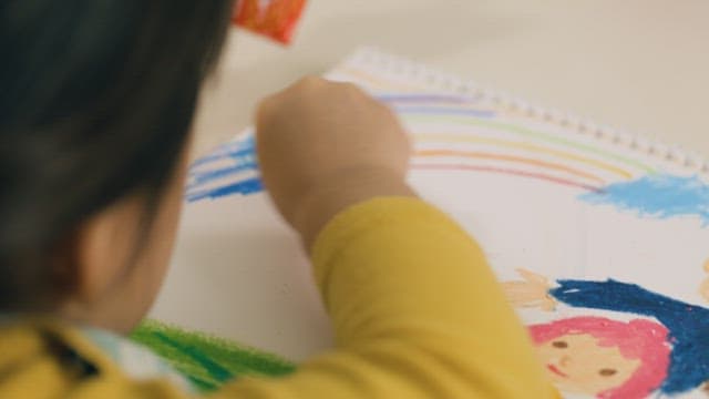 Child Drawing Colorful Pictures in Notebook