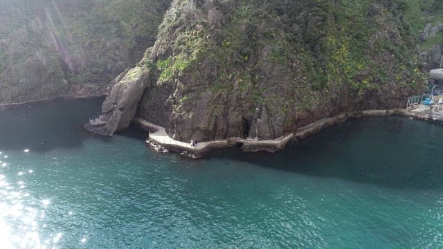 Waves Sparkling in the Sunlight and a Rocky Cliff Walkway