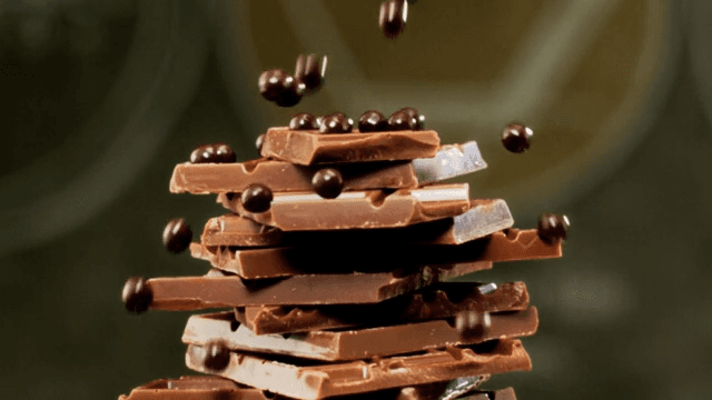 Chocolate balls falling onto a tower of chocolate pieces piled on a plate