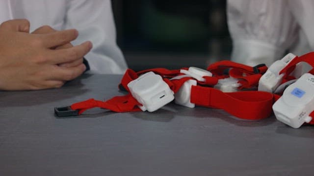 Table with an electronic device on it with a red strap