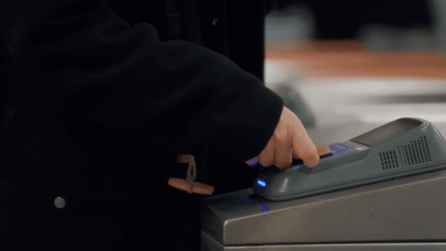 People using card readers at subway turnstiles