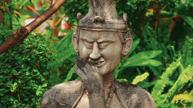 A serene statue in the garden with lush green plants