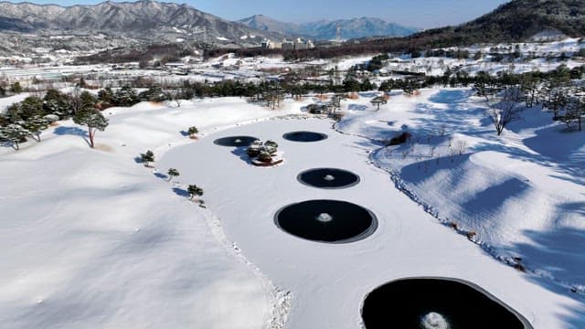 Snow-covered landscape with icy ponds