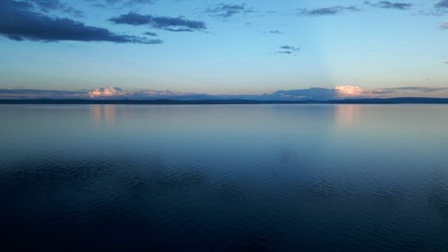 Calm lake with distant clouds at sunset