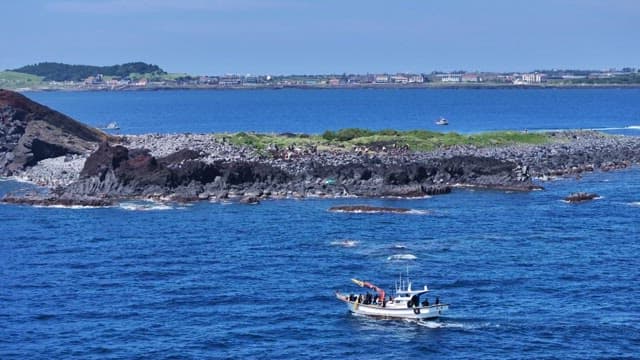 Rocky Island Near Small Boat Floating near on a Sunny Day