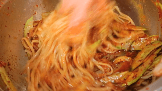 Mixing spicy noodle soup with vegetables
