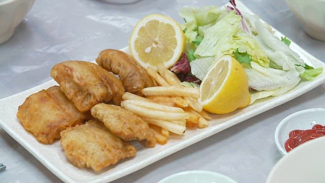 Plate of fried eel, french fries, salad and ball soup