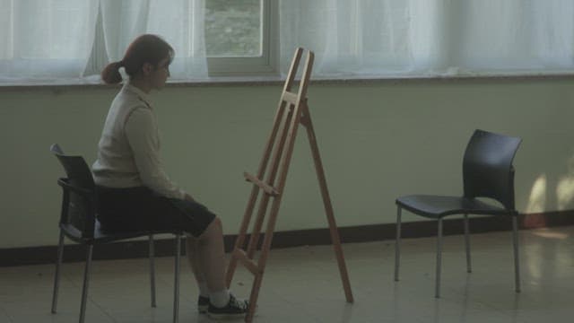 Student sitting thoughtfully by the window in an art room