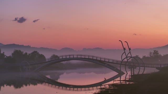 Serene bridge over a misty river at sunset
