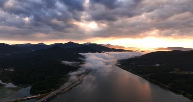 Sunset over mountains and river with clouds