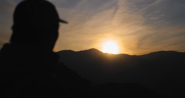 Silhouetted Person Watching Sunrise Over Mountains