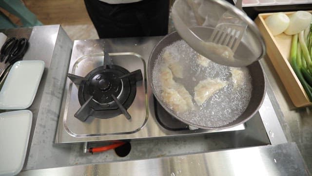 Plating dumplings cooked in a pot on the stove onto a plate