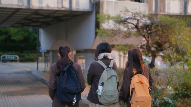 Three students walking under a bridge
