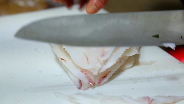 Slicing fresh raw fish on a cutting board