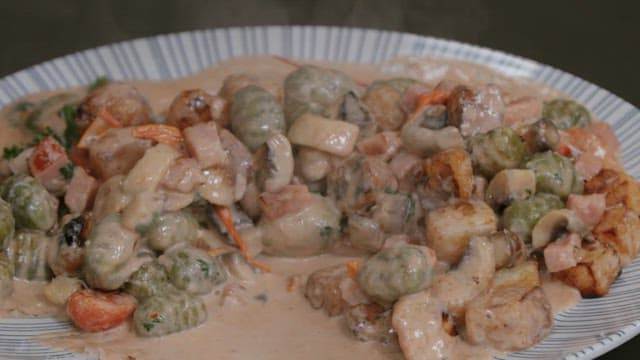 Serving a steaming creamy gnocchi on a plate with a wooden spatula