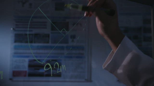 Researcher writing equations on a transparent board