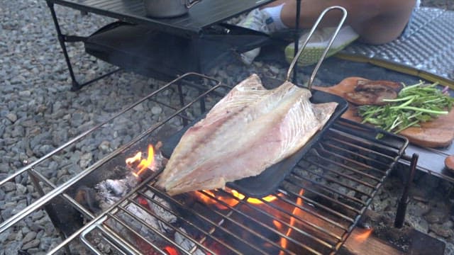Salted mackerel grilled until golden brown on a camping grill