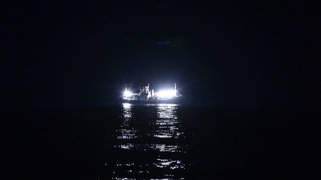Nighttime Fishing Boat with Bright Lights on Sea