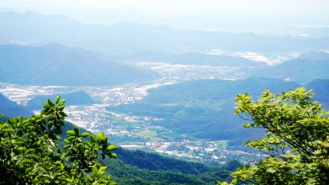 Lush green mountain and a village below on a sunny day