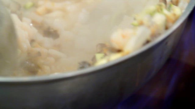 Stir-fried freshwater snail and chopped vegetables in a hot pan