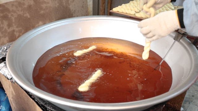 Frying traditional twisted donut dough in oil