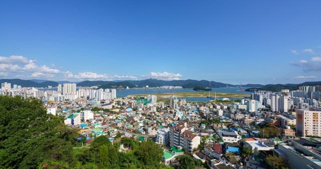 Cityscape with buildings, mountains and sea under the sky from day to night