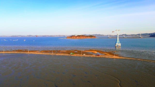 Road on a tidal flat revealed by low tide and cable cars at sunrise