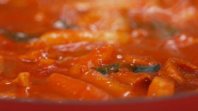 Dipping fries in spicy tteokbokki sauce using a fork