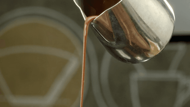 Chocolate syrup poured from a metal pot