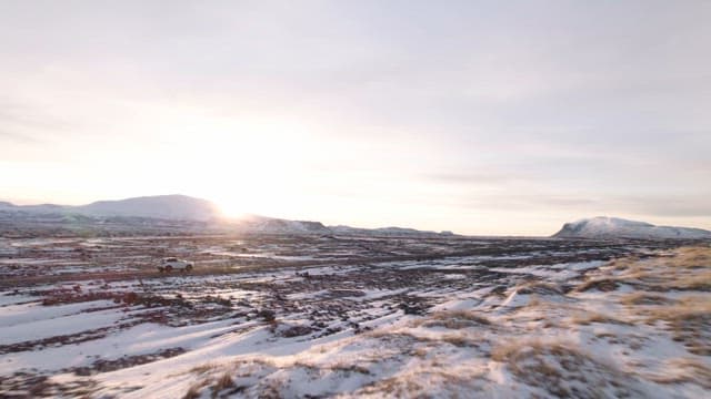 Snowy landscape at sunset with a car