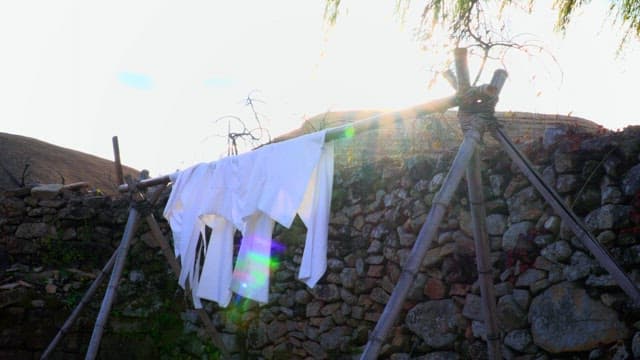 Stone wall with clothes drying in the morning sun in thatched-roof village