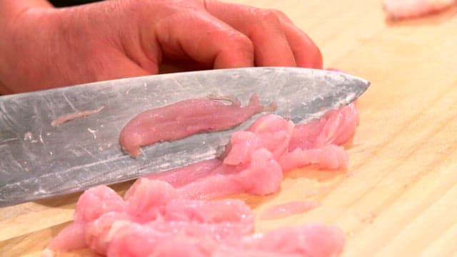 Slicing raw chicken on a wooden board