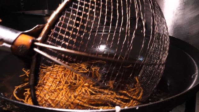 Frying noodles in oil in a wok in the kitchen