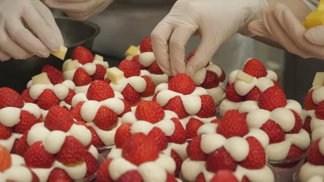 Decorating strawberry dessert with fruits in the kitchen