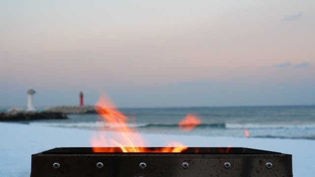 Bonfire burning in a brazier on a snowy beach in the evening