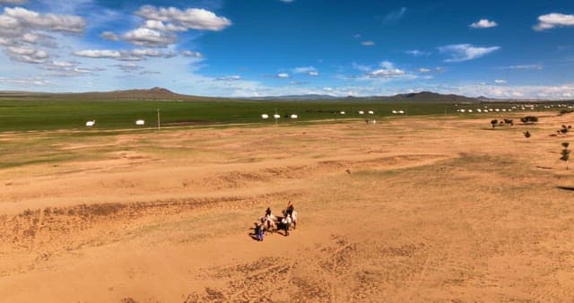 People riding camels in a vast desert