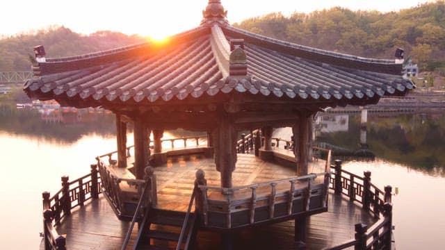 Traditional pavilion on a serene lake at sunset