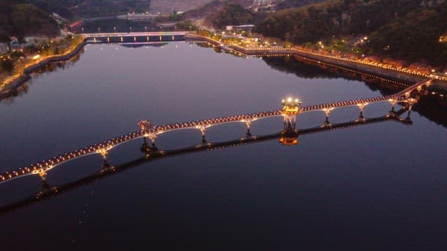 Illuminated bridge over calm river at night