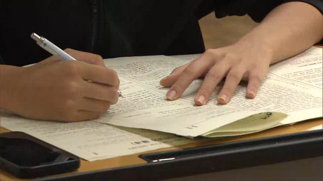 Student Solving Test Questions at Classroom Desk